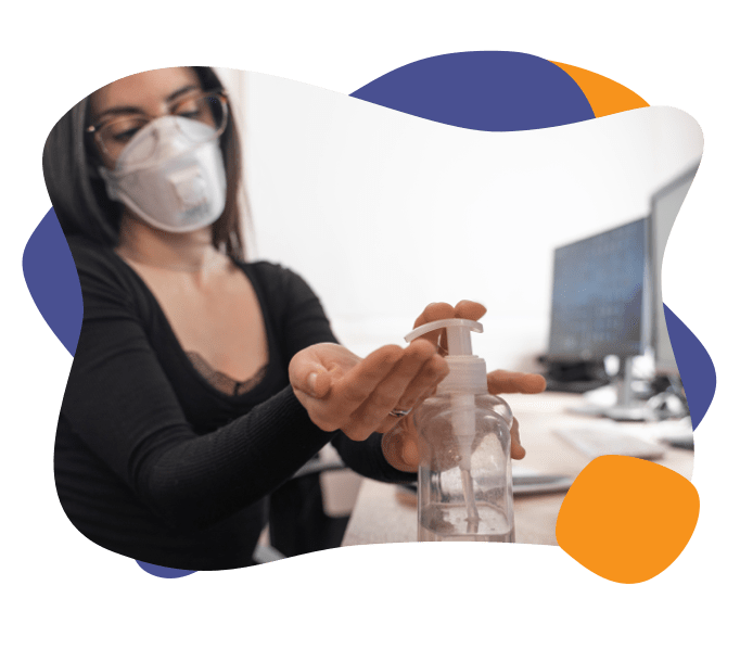 A woman wearing a mask applies hand sanitizer