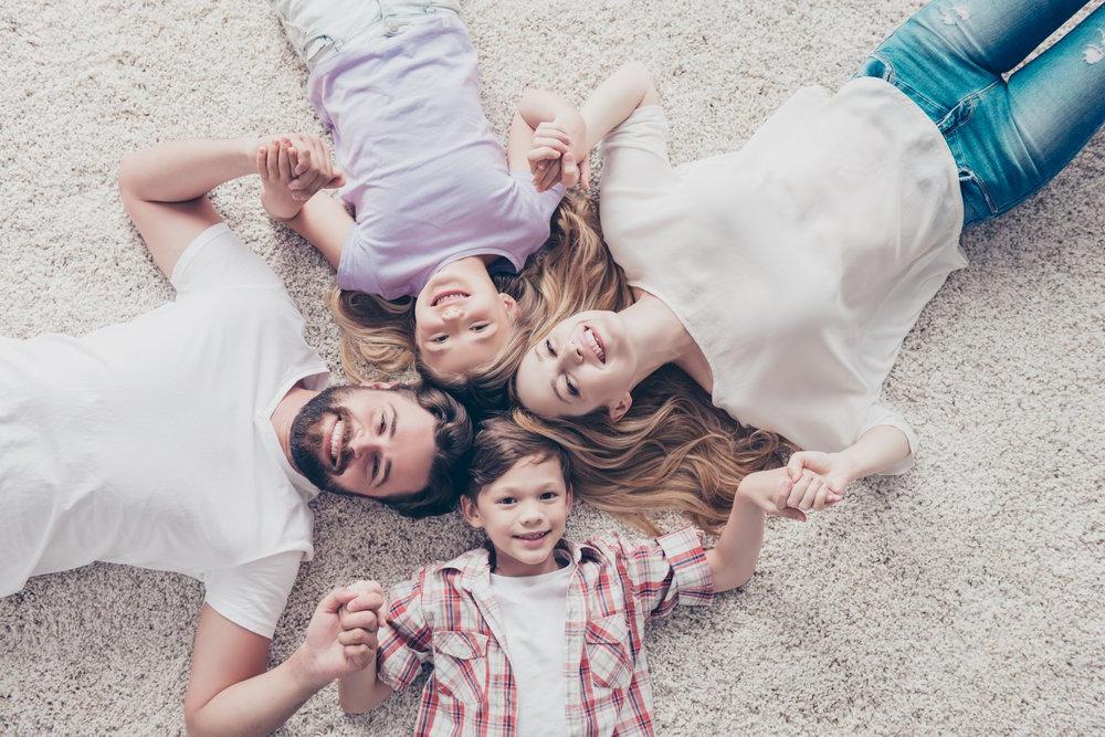 family lying down together on a freshly cleaned carpet