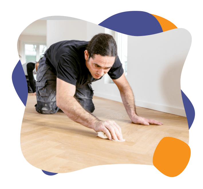 A man scrubbing a glue stain off of a newly installed hardwood floor. 